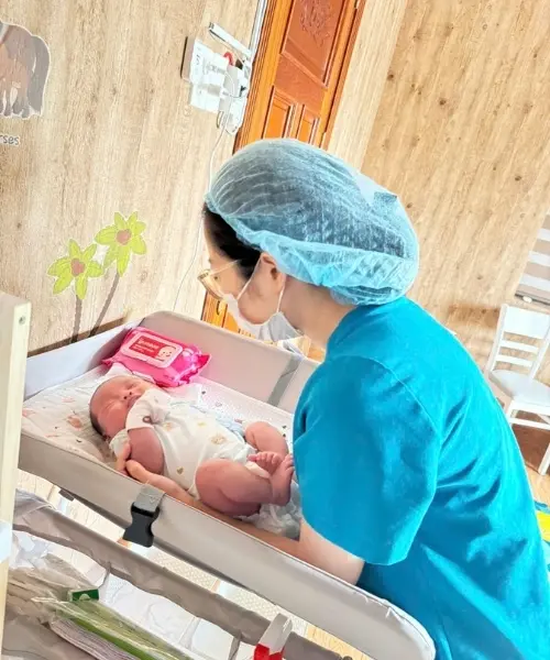 Ánh mắt trìu mến của cô chuyên viên khi đón con vào lòng, yêu thương con như chính tình mẫu tử.